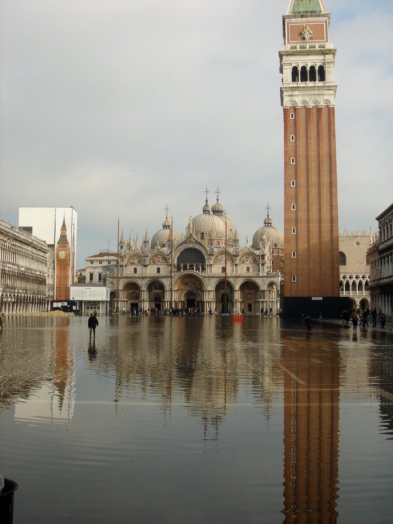 Der Markusplatz bei Acqua alta überflutet, Markusdom und Campanile spiegeln sich an einem grauen Tag im Wasser