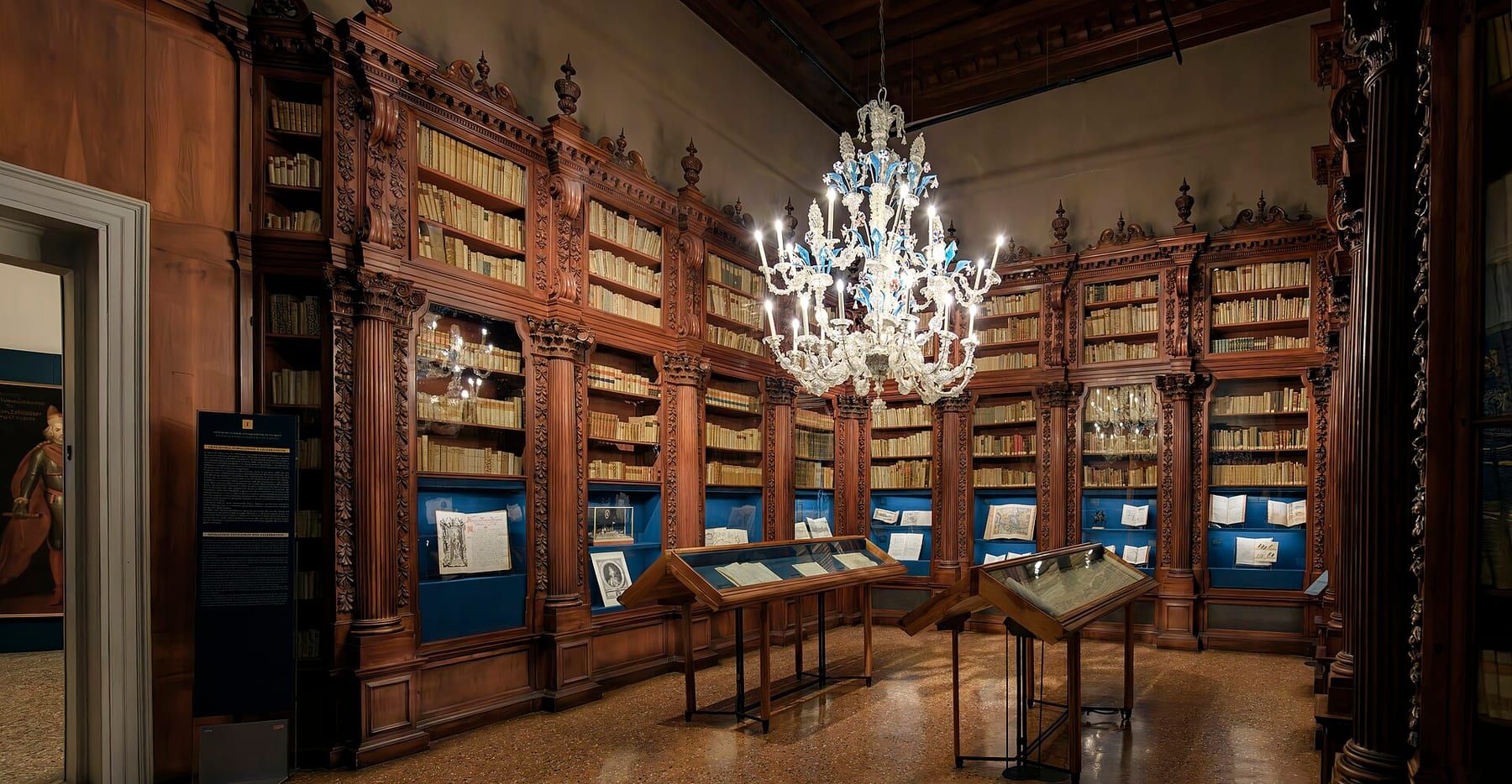 Una sala-biblioteca del Museo Correr con scaffali in legno intagliato, vetrine e un lampadario in vetro di Murano